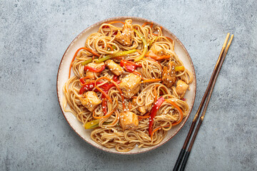 Udon noodles stir fried with chicken meat, carrots, bell peppers and other vegetables are served on...