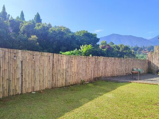Grassy backyard of the house with a wooden fence and beautiful mountain views in the background