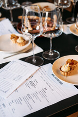Close-up of wine tasting cards and plated desserts surrounded by glassware at a workshop table. Wine workshop, wine knowledge experience, sensory learning, hands-on training