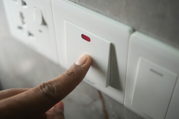 Person pressing a switch for electrical control in a home setting