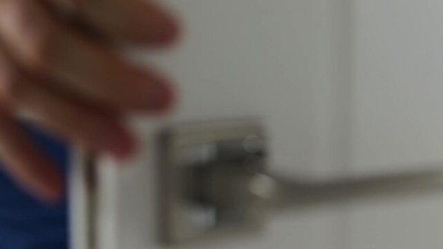 The man opens the white door and enters the room and locks it. Close-up.