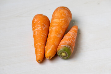 Fresh carrots on a light wooden background. Carrots are a versatile vegetable, promoting eye, skin, digestive, and brain health.