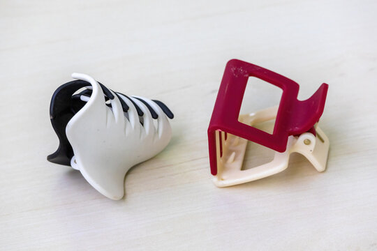 Two plastic hair claw clips (also known as hair crabs or jaw clips) on a light wooden surface. Perfect beauty accessories for everyday use and hair styling.