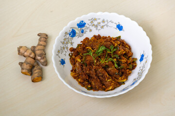 Raw turmeric fry, or kacha holud bhaji, served in a white bowl on a light wooden background. It is a very healthy and tasty food.