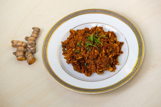 Raw turmeric fry, or kacha holud bhaji, served on a white plate against a light wooden background. It is a very healthy and tasty food.