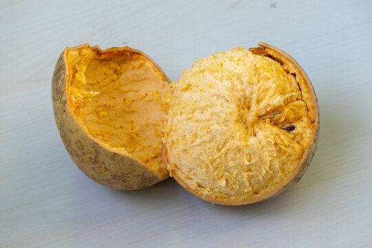 Ripe wood apple or bael fruit, is shown broken open to reveal its juicy flesh interior. Its scientific name is Aegle marmelos, and it is also known as stone apple, Bengal quince, Indian quince, or Bel