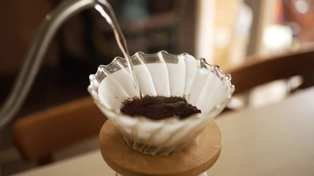 Preparation of filter coffee using the pour-over method with a v60 dripper, hot water is poured over ground coffee beans placed on a paper filter, extracting the coffee's flavor and aroma