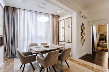A dining room featuring a table, several chairs, and a large window