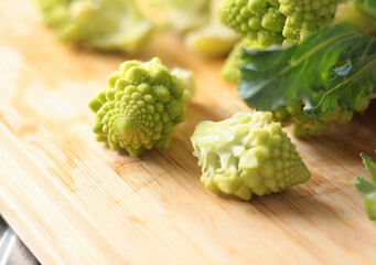 Sliced florets of Romanesco broccoli cabbage on wooden board in kitchen. Healthy eating. Food and green vegetables.