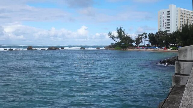 waves on the beach in front of luxury hotel in the condado neighborhood of old san juan puerto rico (famous tourism travel destination caribbean sea) ocean waves water sport paddle boarding surf water