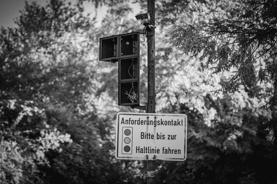 Ein kaputtes Ampelsystem mitten im Gr&uuml;nen &ndash; als h&auml;tte die Natur die Kontrolle zur&uuml;ckerobert. Die Schilder geben Anweisungen, aber die Technik ist l&auml;ngst verstummt. &Uuml;brig bleiben lose Kabel.