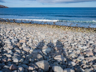 Round stones on the Dragon's Eggs beach in Teriberka, on the Barents Sea in the Murmansk region of...