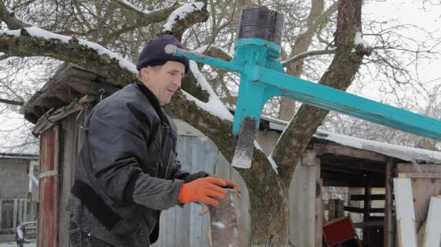 chopping firewood with mechanical wood splitter, mechanical wood splitter for chopping firewood, senior man chops wooden blocks