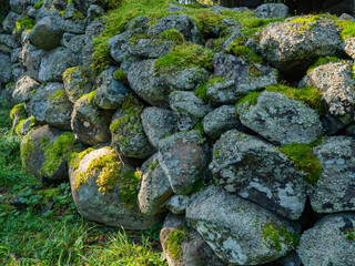 Old fence made of large stones covered with moss in the forest