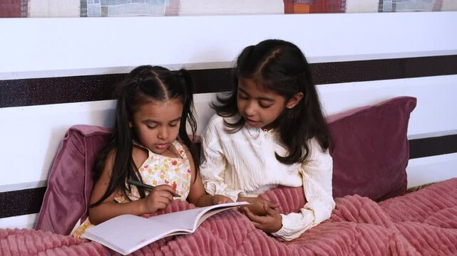 Little indian gild kids studying in bed at home, Children writing in notebook do homework of school. Education and knowledge. india, 4k