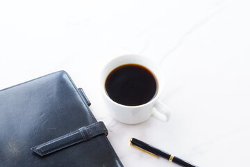 コーヒーを飲みながらシステム手帳でデスクワークをしているイメージ
