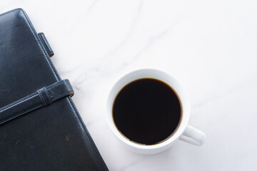 コーヒーを飲みながらシステム手帳でデスクワークをしているイメージ
