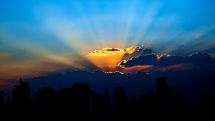 Sunlight Sunbeam or Sunray through clouds or cloudscape over the building tower in Bangkok, Thailand.