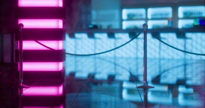 Neon lit entrance with velvet ropes in modern urban space at night