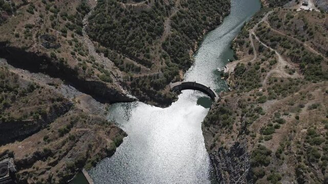 Aerial view of the Foz C&ocirc;a river and the remains of the works for the build of the new dam that was stopped after the findings of the paleolithic rock art. Drone rotating to the left showing old dam.