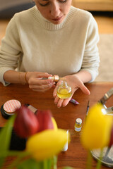 woman applying a makeup primer to her face in front of a mirror. The makeup products are neatly...