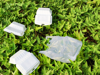 Styrofoam disposable food box on grass. plastic waste. illustration of environmental pollution
