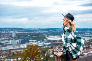 Fototapeta premium Gen Z woman escaping from city life on a hilltop with a view over Stuttgart, Germany
