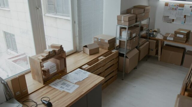 No people high angle view of spacious area of storeroom filled with neatly stacked cardboard boxes of different sizes, two metal shelving units, notice board and wooden pallet
