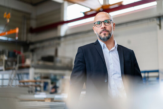 Businessman in a production hall wearing a suit and glasses