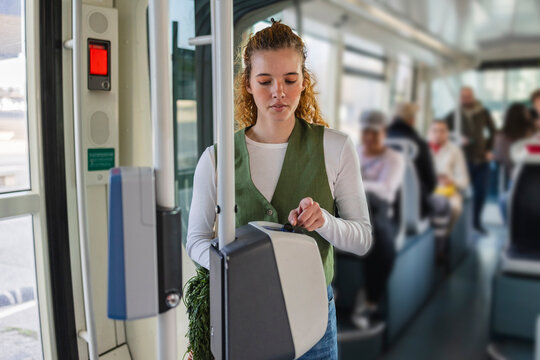 Blonde woman validating ticket on city tram during daytime commute