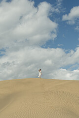 Obraz premium Person Walking on Sandy Dune Under Blue Sky
