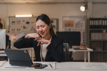 Young professional woman feeling intense pain in her finger while working late at night in the...