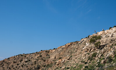 Hikers exploring rocky mountain ridge under clear blue sky
