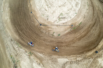 Aerial view of two motocross riders driving their bikes on a dirt track during a race
