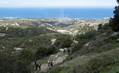 Obraz premium People hiking downhill enjoying breathtaking mediterranean sea view in cyprus