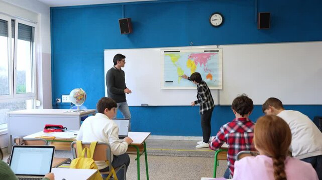 Students actively participating in a geography class, interacting with the teacher and learning about the world map