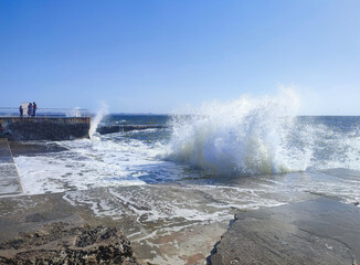 Storm at sea on a sunny summer day. Big sea waves with white foam crashing