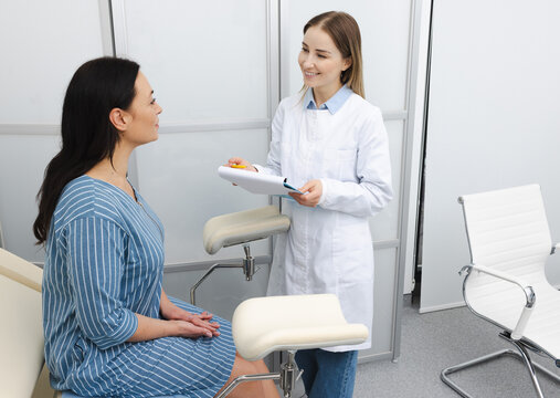 Women's health, gynecology. Patient sitting in a gynecological chair during a consultation with her attending gynecologist in a modern clinic