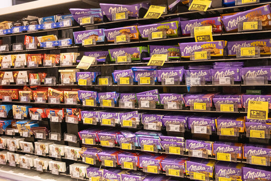 Poznan, Poland - March 22, 2025: Milka chocolate bars in colorful packaging arranged on supermarket shelf with price tags and promotional labels in Polish retail store candy aisle