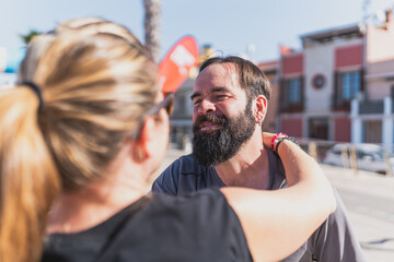 Disabled man smiling warmly while interacting with woman in sunny urban setting - Man with mobility...