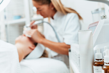 Young woman receiving hydra facial treatment for exfoliation, rejuvenation and hydration of her face skin. Modern facial hydro microdermabrasion peeling beauty procedure. Hydra vacuum cleaner.