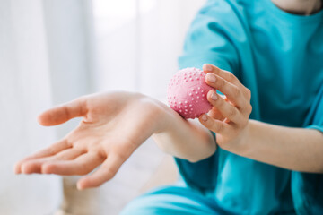 Close-up of woman applying a pink massage ball to her forearm. Tactile wellness, sensory therapy, mindful touch, daily stress relief