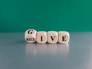 Cubes form the words give and receive. Beautiful green background, gray table. Business concept.