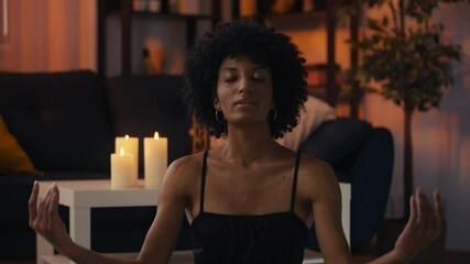 Concentrated African American female in lotus position, meditating at home