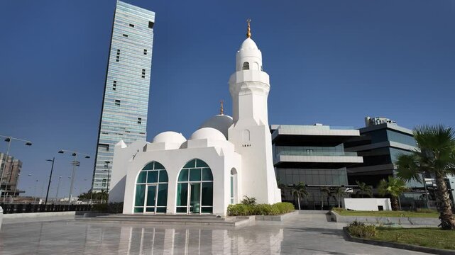 Modern skyscrapers and a white mosque blend seamlessly into the urban landscape of Jeddah, Saudi Arabia, showcasing a harmonious coexistence of tradition and progress