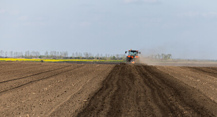 Naklejka premium Tractor is preparing the land at dusk