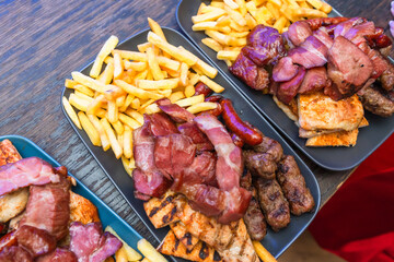 Delicious Grilled Meat Platter With Crispy French Fries On Rustic Wooden Table