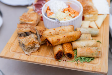 Gourmet Assorted Appetizers On Wooden Platter Featuring Crisp Spring Rolls And Dips