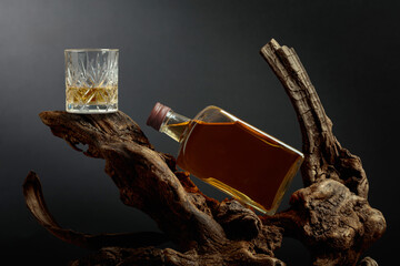 Bottle and glass of whiskey on a old snags.