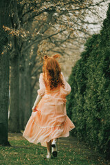 Running barefoot through alley of trees, fabric swirling like wind, young woman flees something...